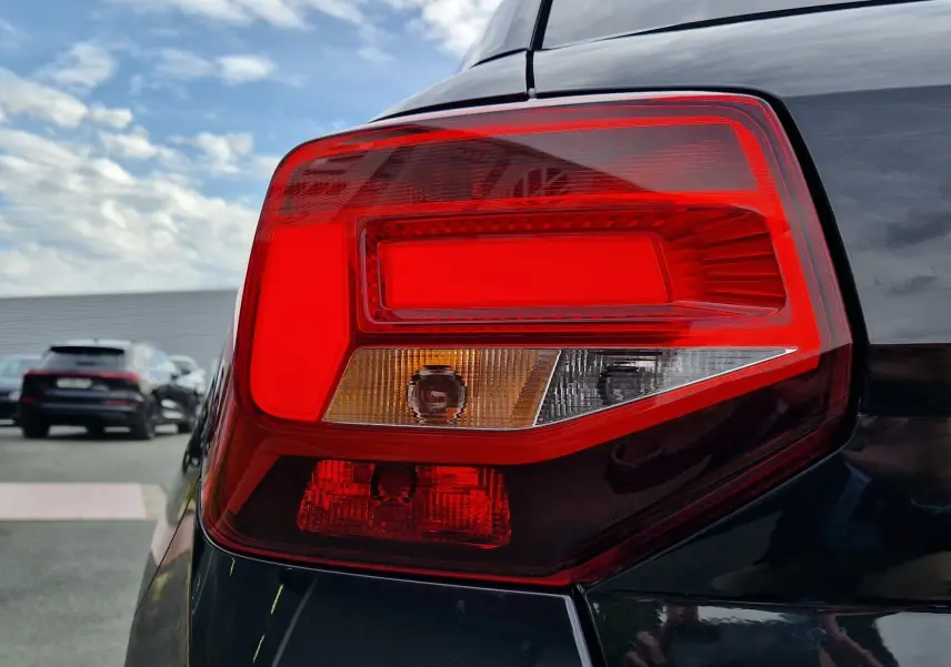 Gros plan sur le feu arrière droit d'un Audi Q2 35 TFSI noir mito metal, soulignant ses lignes nettes et modernes.