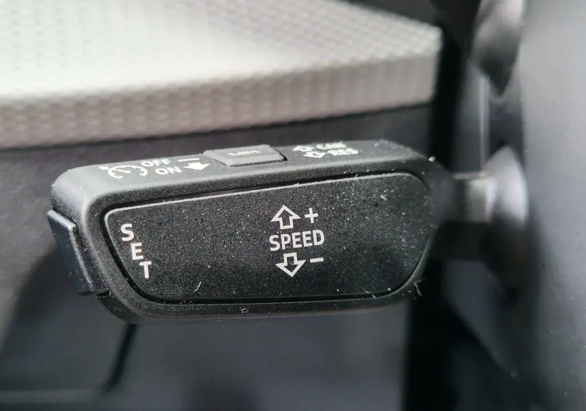 Gros plan sur la commande de régulateur de vitesse noir à l'intérieur de l'Audi Q2 35 TFSI 2023.