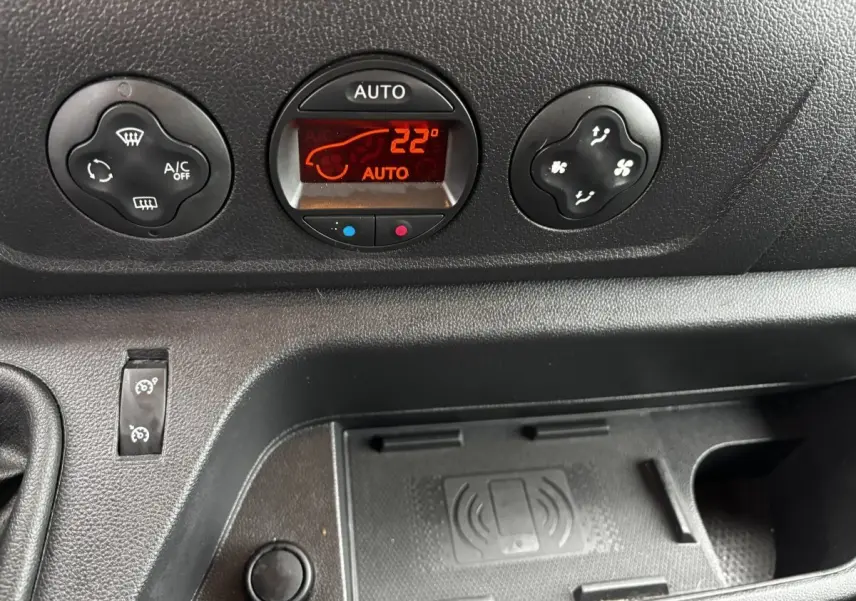 Gros plan sur la console centrale noire du Renault Master 2020, avec commandes climatisation et zone de recharge sans fil.