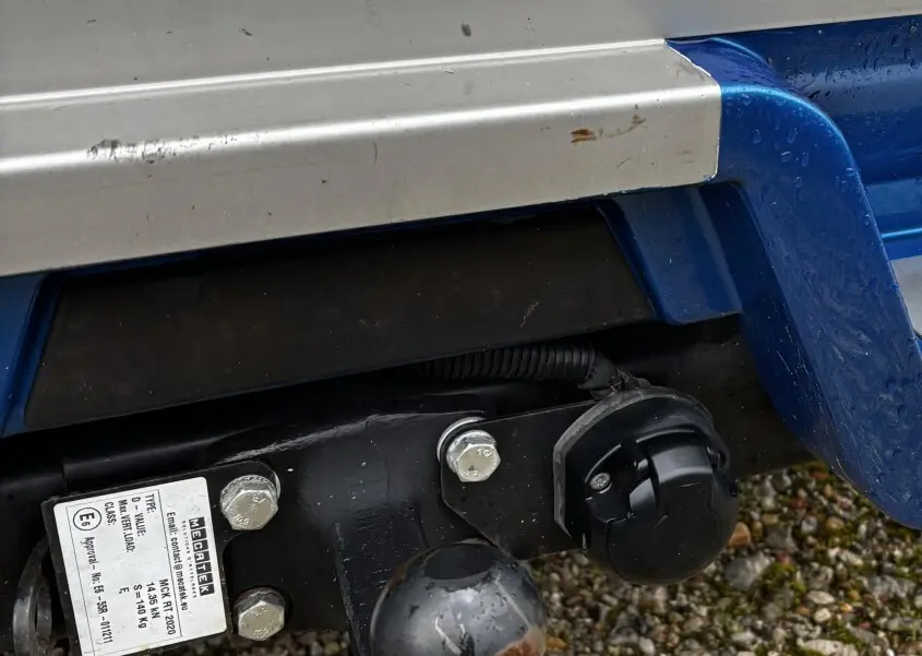 Gros plan sur l'attelage remorque noir rouillé sous le pare-chocs arrière bleu du Renault Master 2020.