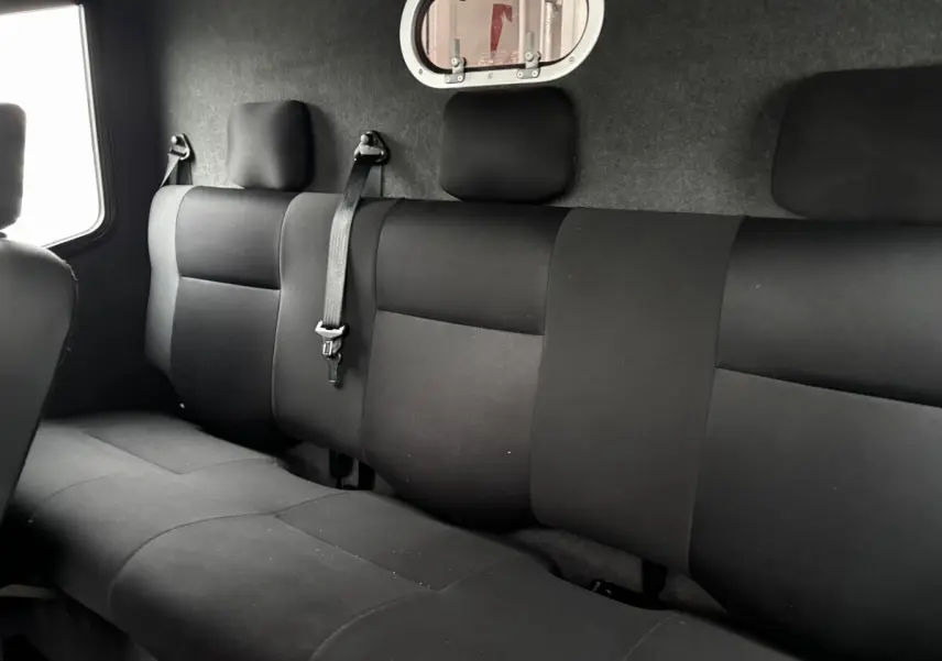 Vue intérieure du côté arrière droit montrant la banquette noire du Renault Master avec une cloison vitrée.