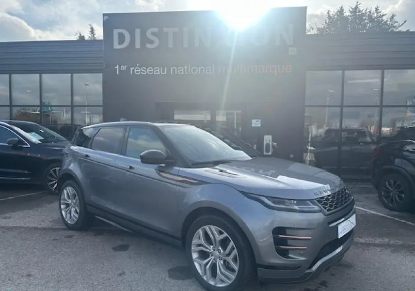 Vue 3/4 avant droit d'un Range Rover Evoque gris foncé avec toit noir et jantes 20 pouces, stationné devant un bâtiment.