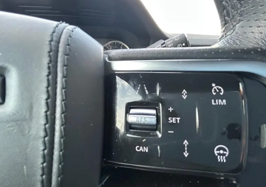 Gros plan sur les commandes de régulateur de vitesse sur le volant cuir noir du Range Rover Evoque gris foncé.