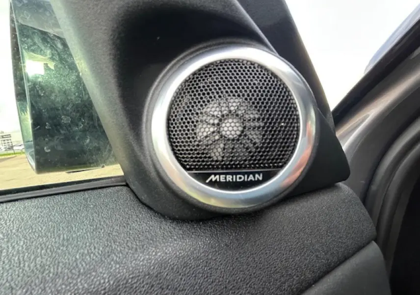 Gros plan sur le haut-parleur Meridian intégré à la porte côté gauche du Range Rover Evoque gris foncé 2022.