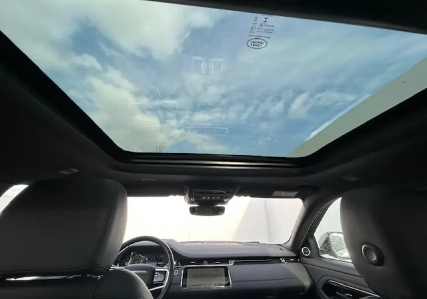 Vue intérieure avant du Range Rover Evoque gris foncé 2022 avec toit ouvrant panoramique et tableau de bord moderne.