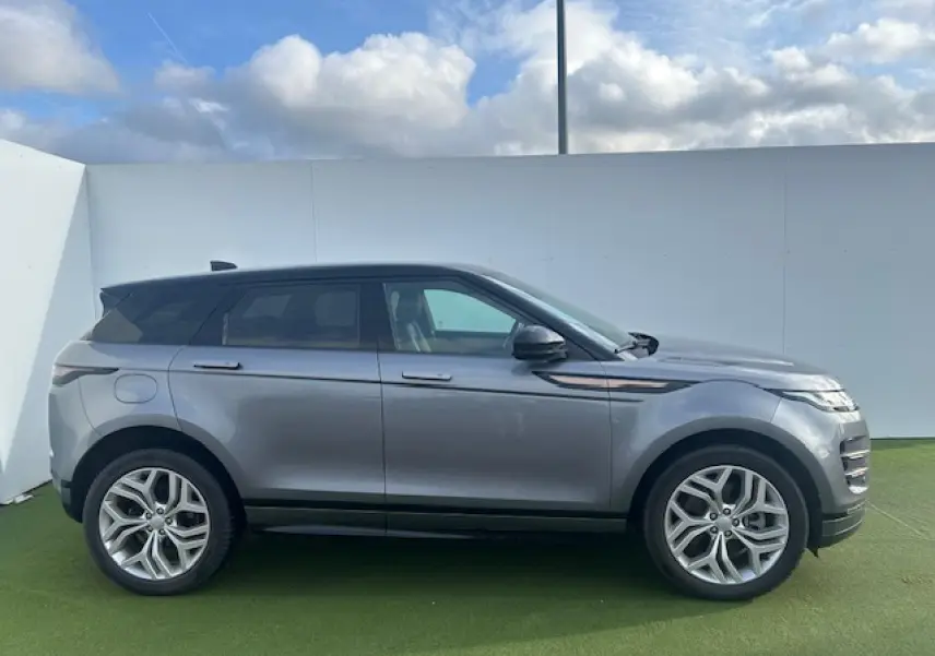 Vue latérale droite d'un Range Rover Evoque gris foncé avec toit noir et jantes 20 pouces sur fond extérieur clair.