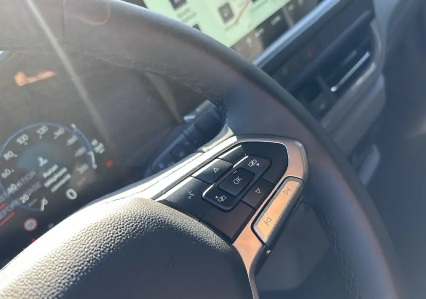 Gros plan sur le volant multifonctions du Volkswagen Transporter TDI 170 DSG Procab L1, avec tableau de bord numérique en arrière-plan.