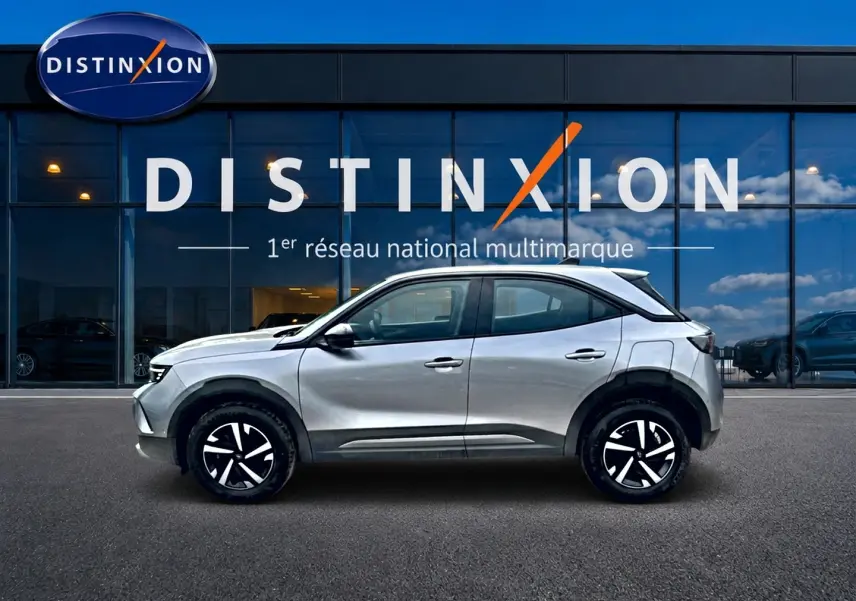Opel Mokka gris vue de profil côté gauche, avec jantes noires et toit contrasté blanc devant showroom Distinxion.