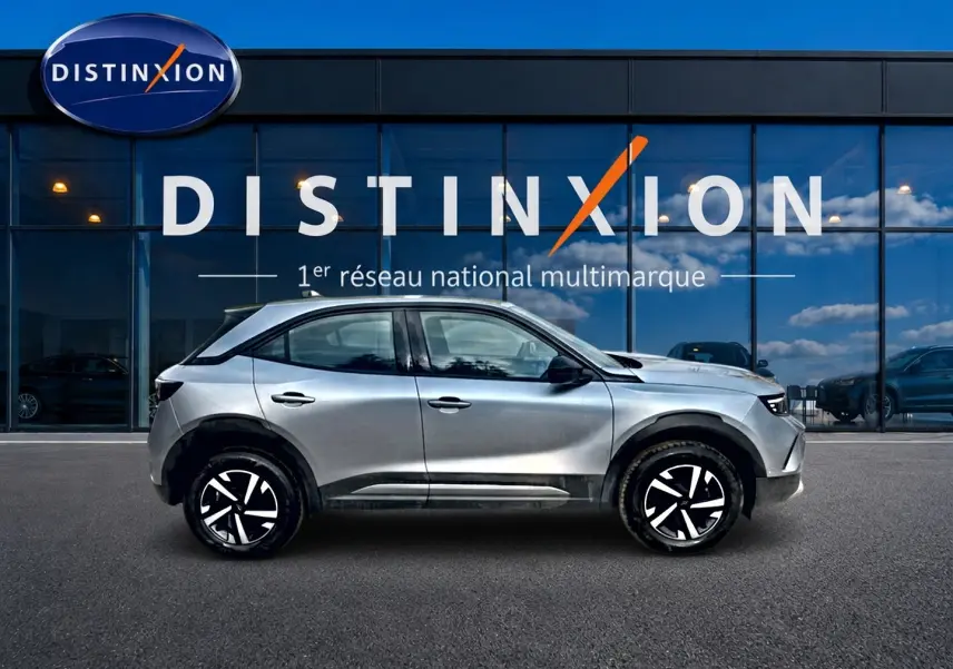 Opel Mokka gris vue de profil côté gauche, avec jantes noires et blanches, devant une vitrine Distinxion.