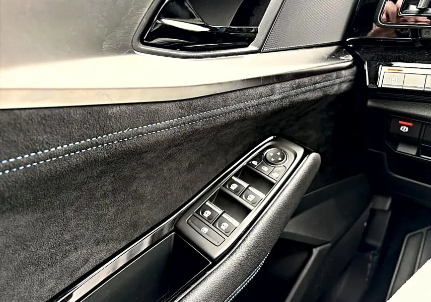 Gros plan sur la porte côté conducteur du Renault Austral gris schiste, avec commandes des vitres et surpiqûres bleues.