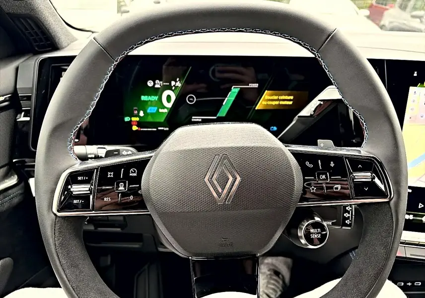 Vue rapprochée du volant gris et noir du Renault Austral 2026 avec commandes multifonctions et écran numérique en arrière-plan.