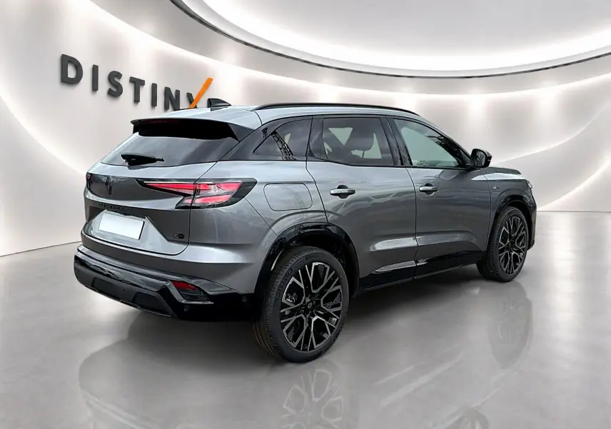 Vue 3/4 arrière droite du Renault Austral gris schiste avec jantes alu noires et toit noir contrasté dans un showroom.