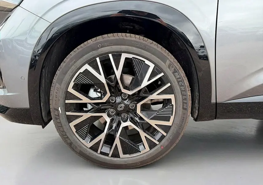 Gros plan sur la roue avant droite du Renault Austral gris schiste avec jante alu au design géométrique noir et argent.
