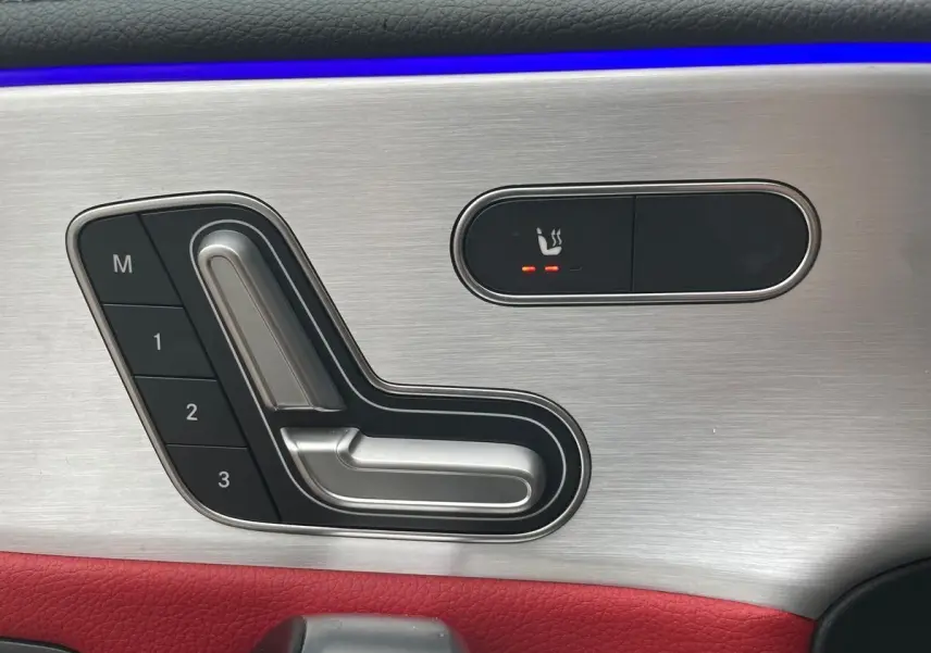 Détail des commandes de réglage de siège avec mémoire et chauffage sur la portière côté conducteur d'une Mercedes CLA Shooting Brake blanche 2021.