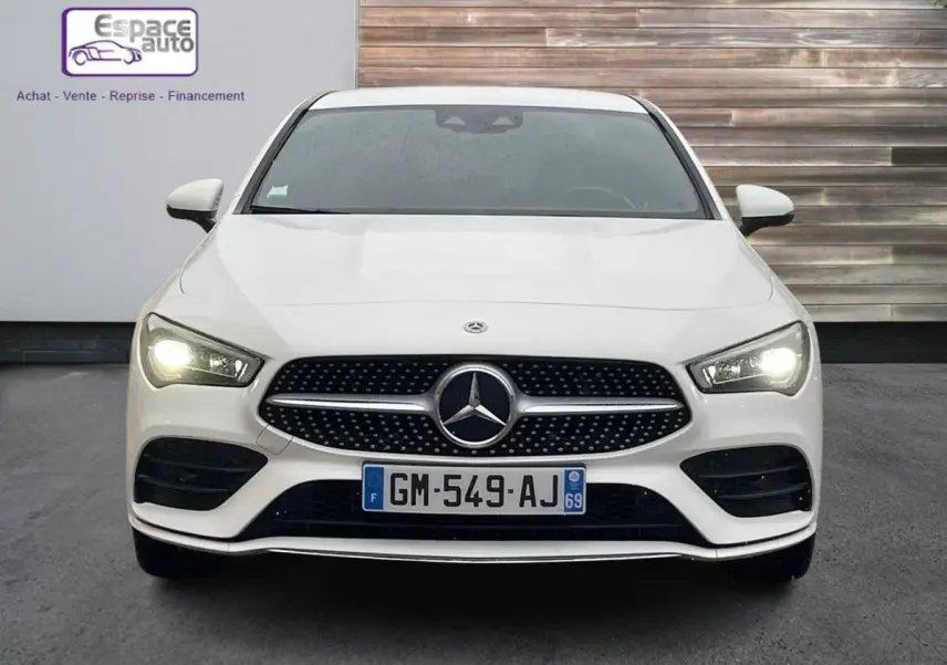 Vue frontale d'une Mercedes Classe CLA Shooting Brake blanche de 2021 avec phares allumés et calandre AMG distinctive.