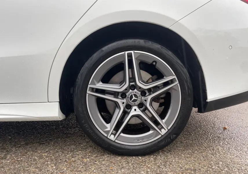 Gros plan sur la roue arrière droite blanche d'une Mercedes Classe CLA Shooting Brake AMG Line 2021 avec jante étoile AMG.