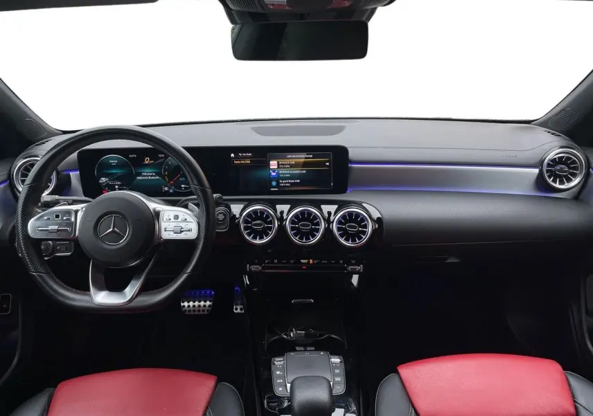 Intérieur de Mercedes Classe CLA Shooting Brake blanc 2021, vue frontale du tableau de bord avec sièges rouges et éclairage bleu.