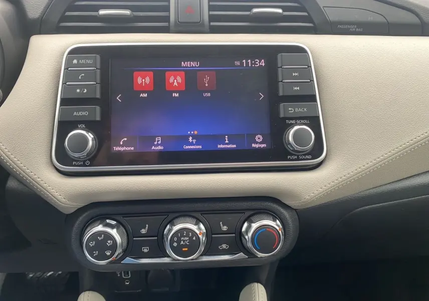 Vue rapprochée de la console centrale beige et noire de la Nissan Micra 2022 avec écran tactile et commandes de climatisation.