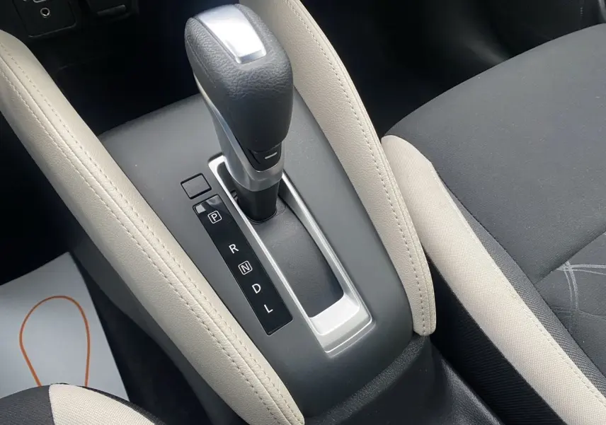Le levier de vitesses automatique noir et argenté de la Nissan Micra 2022, entouré d’un accoudoir beige et siège tissu noir-beige.