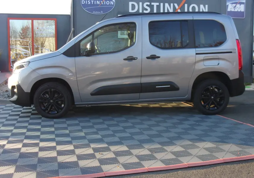 Vue de profil côté gauche d'un Citroën Berlingo gris Artense avec jantes noires et protections latérales noires.