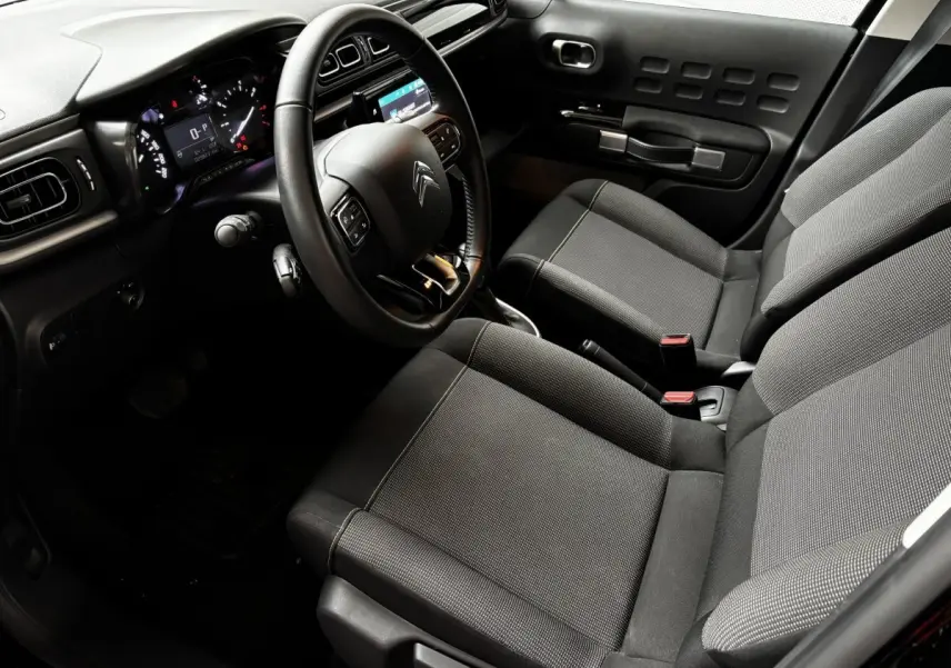 Vue intérieure de la Citroën C3 PureTech 110 2024, côté conducteur, avec volant multifonctions et sièges tissu gris.