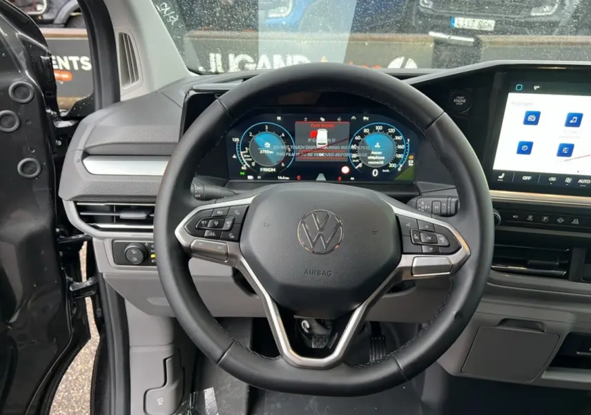 Vue intérieure centrée sur le volant noir et le tableau de bord digital du Volkswagen Transporter TDI 170 DSG 2026.