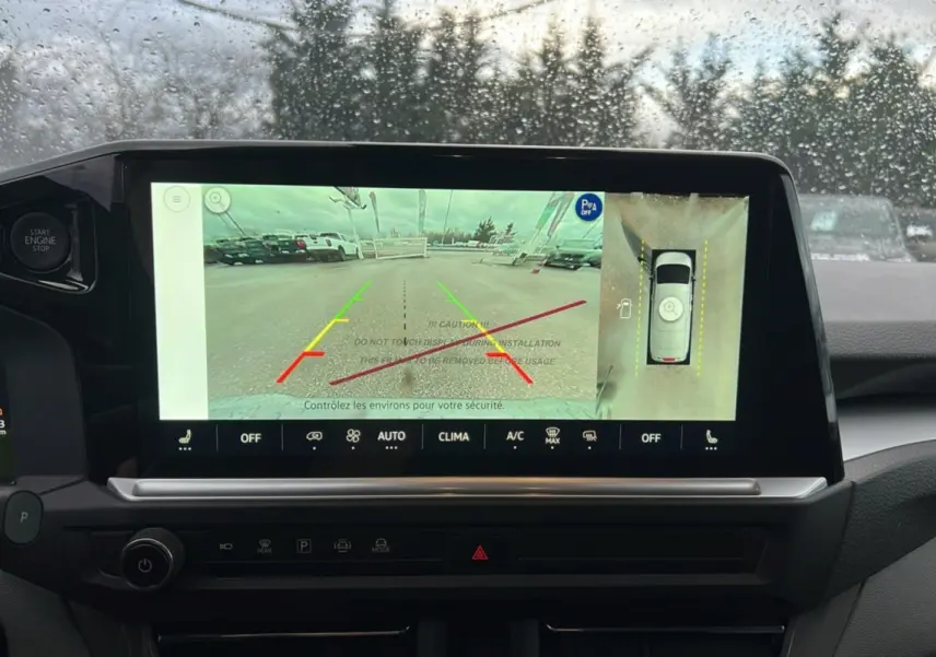 Vue intérieure du tableau de bord du Volkswagen Transporter TDI 170 DSG ProCab L2 avec écran de caméra 360 et pluie sur le pare-brise.