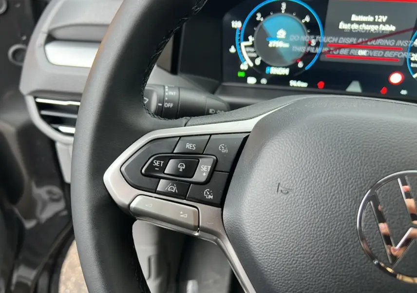 Gros plan sur le volant multifonctions noir du Volkswagen Transporter TDI 170 DSG 2026 avec tableau de bord digital en arrière-plan.