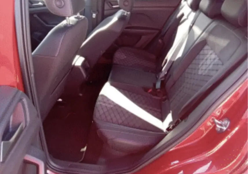 Vue intérieure côté arrière droit du Volkswagen T-Cross rouge métal 2025, sièges arrière en tissu noir à motif losange.