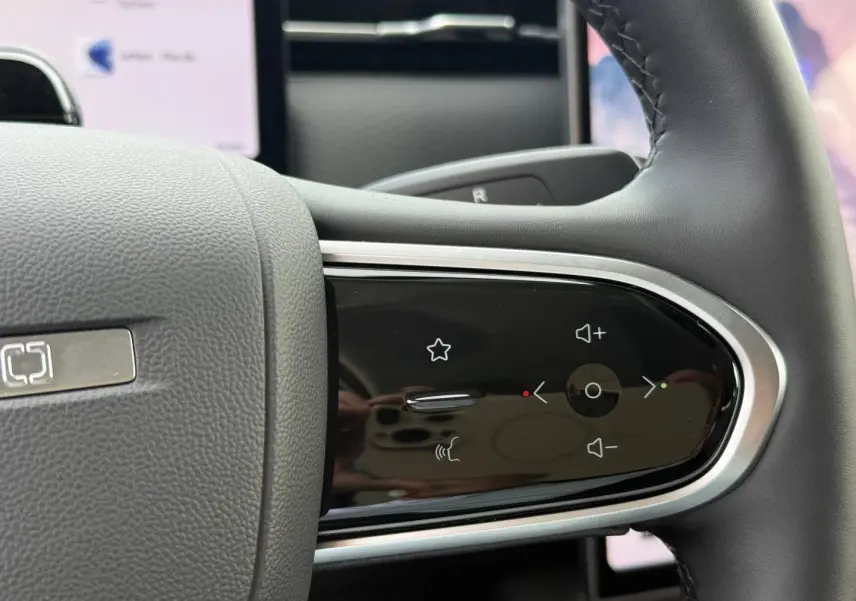 Gros plan sur les commandes tactiles noires du volant côté droit du JAECOO J7 blanc, avec finition chromée.