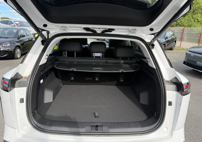 Coffre ouvert vu de l'arrière d'un JAECOO J7 blanc, avec banquette arrière et cache-bagages visibles.