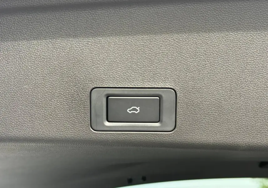 Bouton d'ouverture électrique du coffre sur la garniture intérieure d'un JAECOO J7 blanc hybride rechargeable.