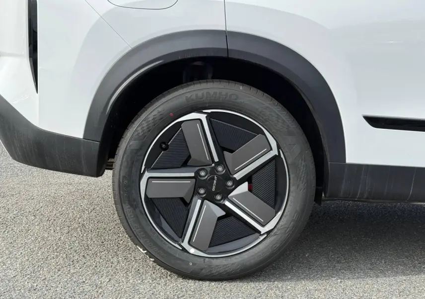 Gros plan sur la roue arrière droite du JAECOO J7 blanc, avec jante alu noire et argentée au design moderne.