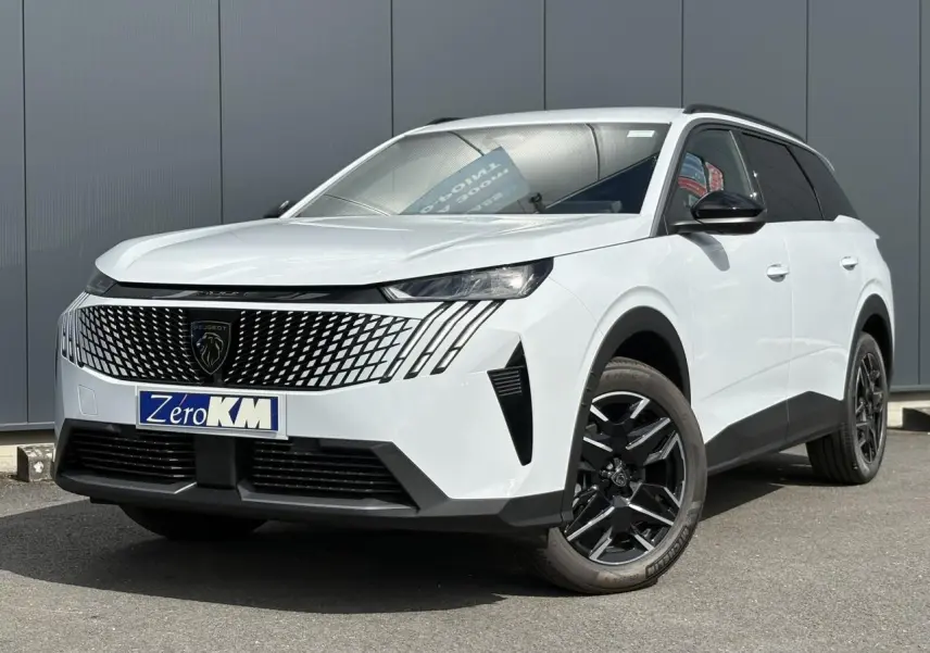 Peugeot 5008 blanc Okénite en 3/4 avant droit, avec calandre noire distinctive et jantes alliage noires.