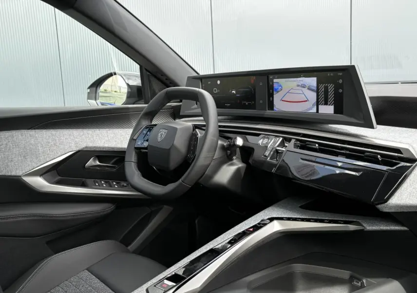 Vue intérieure côté conducteur du Peugeot 5008 Hybrid 2025, avec tableau de bord numérique et volant compact noir.