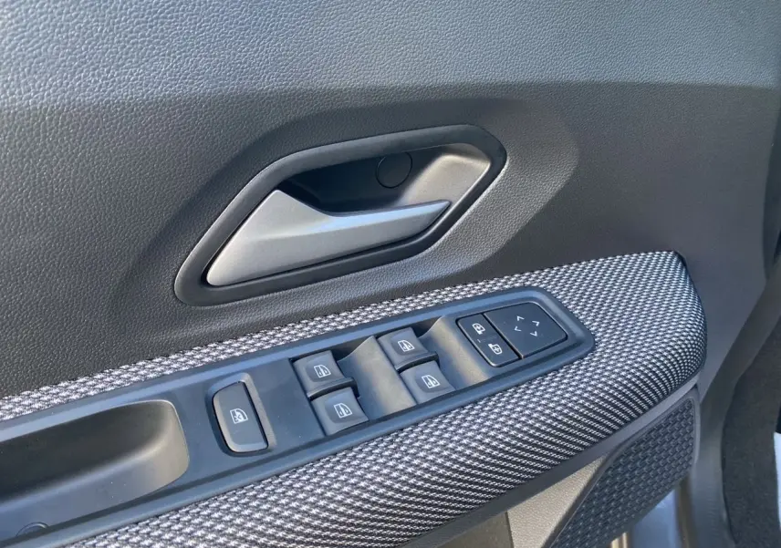 Gros plan sur la commande des vitres électriques côté conducteur avec insert gris texturé dans une Dacia Sandero Stepway 2025.