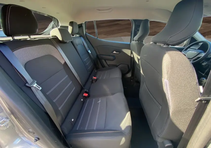Vue intérieure côté gauche montrant les sièges arrière noirs et le tableau de bord partiel d'une Dacia Sandero Stepway 2025.