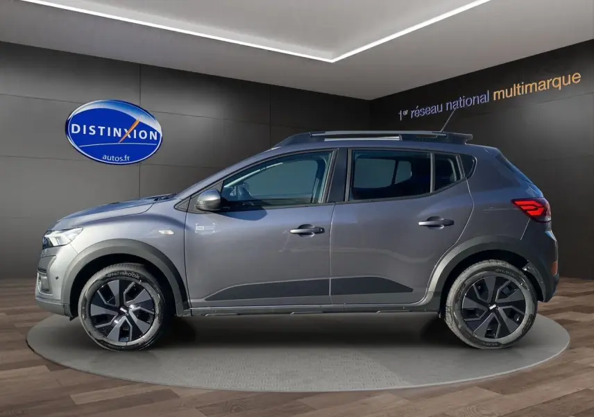 Profil droit d'une Dacia Sandero Stepway 2025 gris schiste avec barres de toit et jantes noires distinctives.