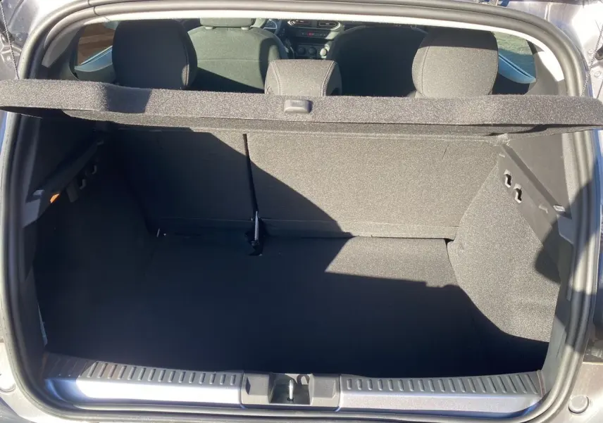 Coffre ouvert d'une Dacia Sandero Stepway gris schiste, vue arrière montrant l'espace de chargement et la banquette arrière.