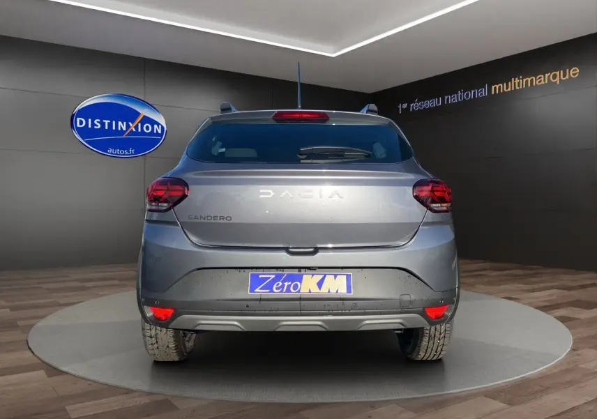 Vue arrière d'une Dacia Sandero Stepway gris schiste avec feux LED et plaque Zero KM en showroom.