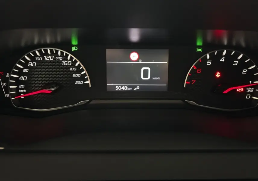 Vue rapprochée du combiné d'instruments numérique de la Peugeot 208 gris clair, affichant 0 km/h et 5048 km au compteur.