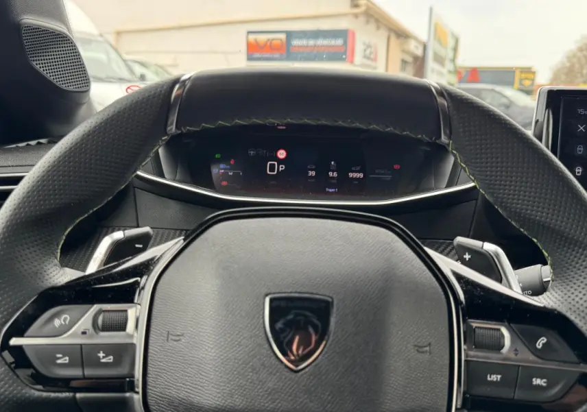 Vue rapprochée du volant Peugeot 208 Hybrid 110 e-DCS6 GT gris avec commandes intégrées et tableau de bord numérique.