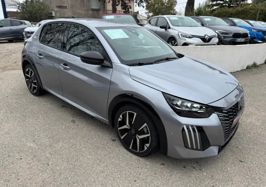 Peugeot 208 Hybrid gris vue 3/4 avant droit, jantes alliage 17 pouces et rétroviseurs noirs visibles.