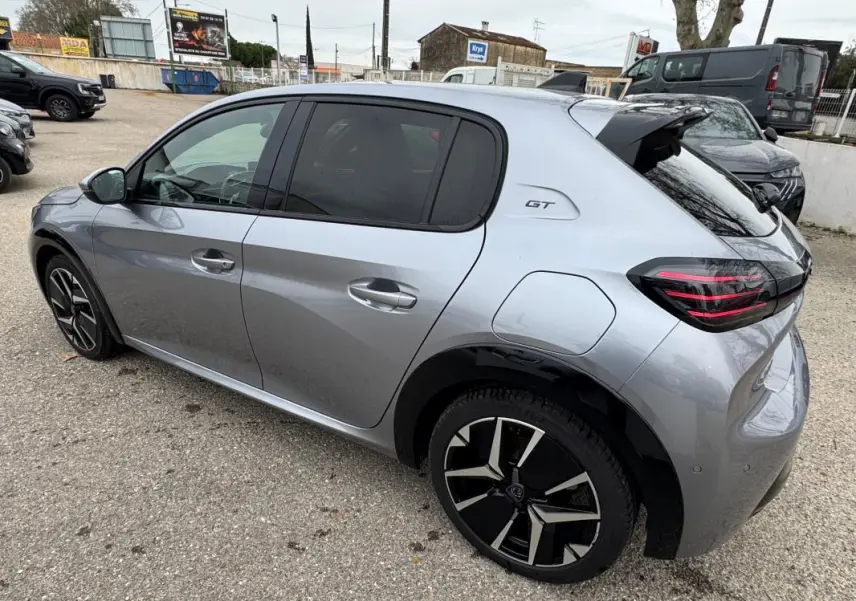 Vue 3/4 arrière droite d'une Peugeot 208 Hybrid 110 gris métallisé avec jantes alliage 17 pouces et badge GT.