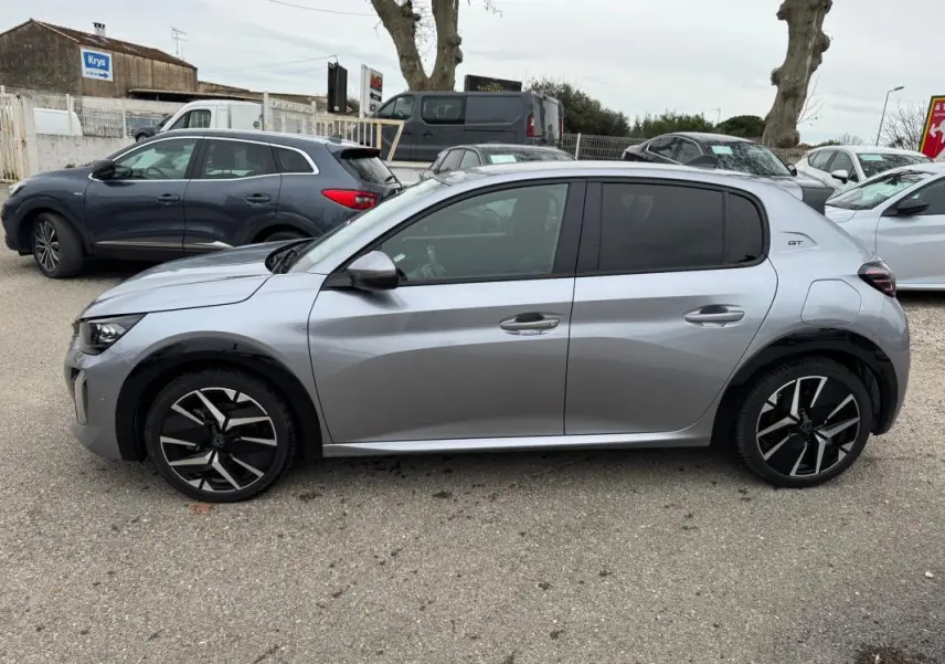 Vue de profil côté gauche d'une Peugeot 208 gris métallisé Hybrid 110 e-DCS6 GT avec jantes alliage 17 pouces et antenne requin.