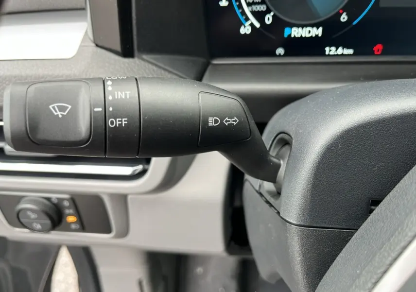 Gros plan sur la manette de clignotant et essuie-glace du Volkswagen Transporter TDI 170 DSG 2026, tableau de bord partiel visible.