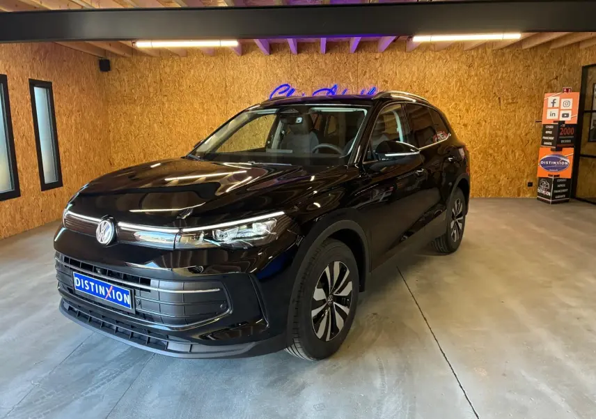 Volkswagen Tiguan 1.5 TSI noir grenadilla métal en 3/4 avant droit dans un showroom intérieur.