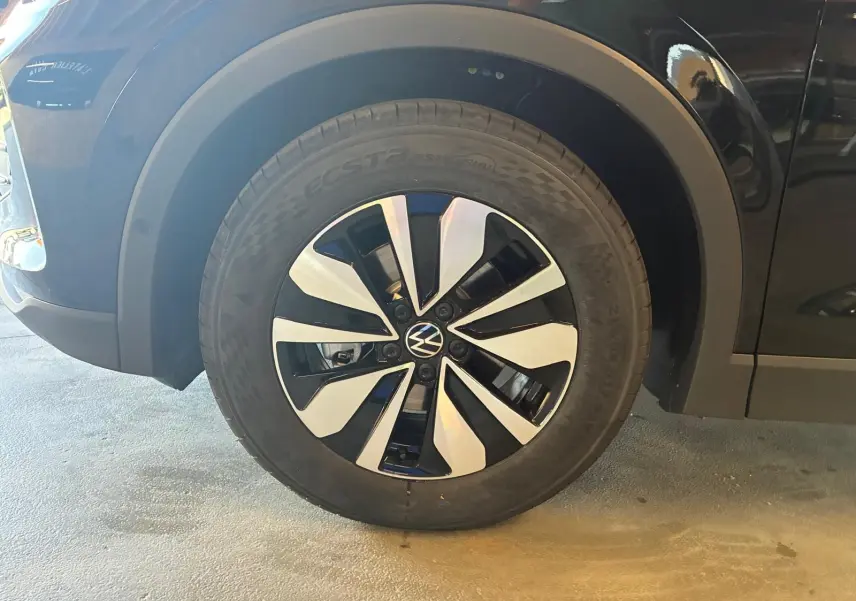 Gros plan sur la roue avant gauche du Volkswagen Tiguan noir Grenadilla Métal avec jante alliage bicolore distinctive.