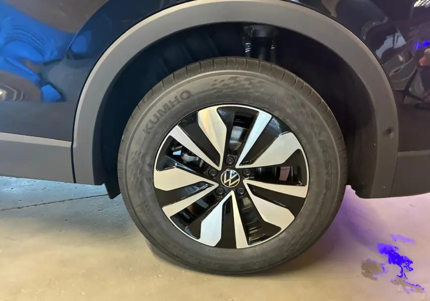 Gros plan sur la roue avant gauche noire grenadilla métal du Volkswagen Tiguan 1.5 TSI 130 DSG LIFE 30 YEARS avec jante bicolore.