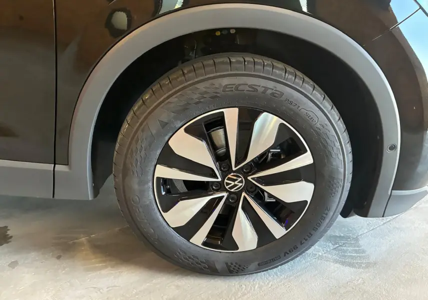 Gros plan sur la roue avant droite noire grenadilla métal du Volkswagen Tiguan 1.5 TSI 130 DSG Life 30 Years avec jante alliage bicolore.